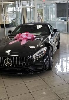 a black car with a pink bow on it's hood in a showroom