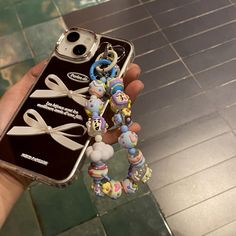 someone holding up their cell phone case with some beads on it and an earring