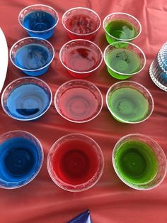 there are many cups with different colored liquids in them on the table next to each other