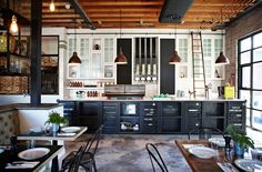 an industrial style kitchen with white cabinets and black counter tops, along with ladders hanging from the ceiling