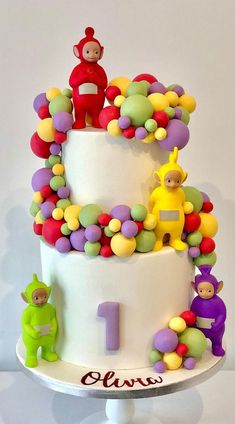 a three tiered cake decorated with colorful candies and figures on it's side