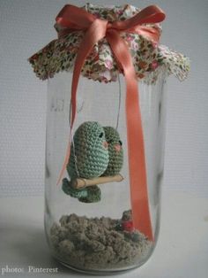 a glass jar filled with sand and a small green cactus sitting on top of it