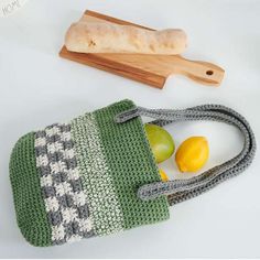 a crocheted bag with lemons and bread on the table next to it