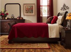 a bed room with a neatly made bed and wooden floors