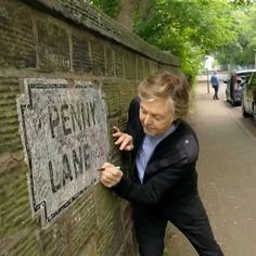 a woman leaning against a brick wall writing on the side of it that says penn lane