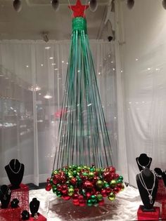 there is a christmas tree made out of glass balls and other ornaments on display in the window