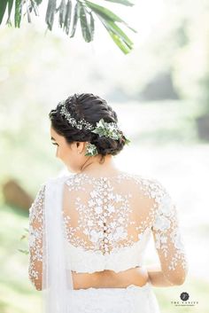 a woman wearing a wedding dress and veil with flowers in her hair standing under a palm tree