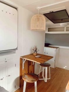 a small kitchen with white cabinets and wooden table in the center, along with two stools