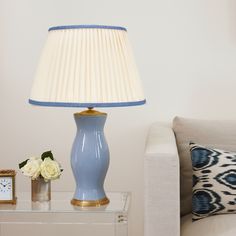 a blue vase sitting on top of a glass table next to a lamp and clock