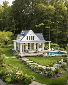 a white house with a pool in the middle and landscaping around it, surrounded by trees