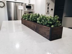 a kitchen counter with a wooden planter on it and a clock in the background