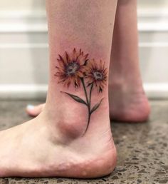 a woman's foot with a tattoo of two sunflowers on the ankle