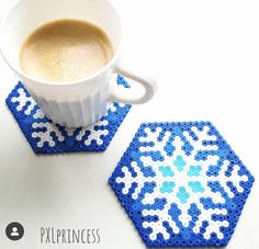 a cup of coffee sitting next to two coasters with blue and white designs on them