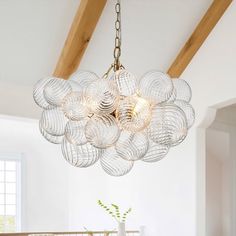 a chandelier hanging from the ceiling in a room with white walls and wooden beams