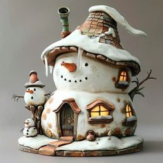 a ceramic house with two snowmen in front of it and a light on the roof