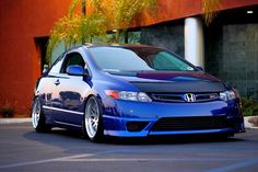 a blue honda civic is parked in front of a building with palm trees behind it