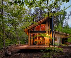 a small cabin in the woods surrounded by trees and rocks is lit up at night