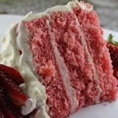 a piece of red velvet cake with white frosting and strawberries on the side