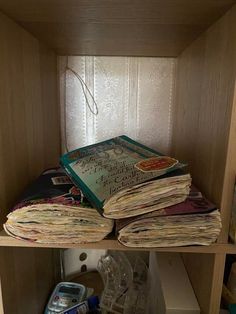 several books are stacked on top of each other in a bookcase with papers scattered about it