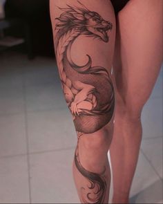 a woman's leg with a dragon tattoo on it