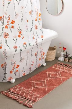 a bathroom with a bathtub, rug and mirror on the floor in front of it