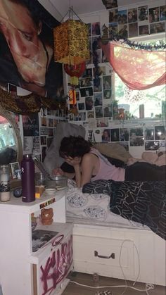 a woman sitting on top of a bed in a room filled with pictures and posters