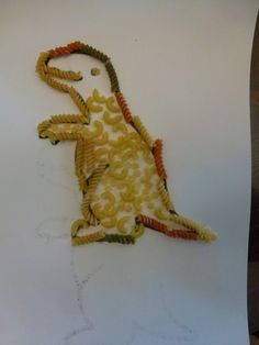 an animal made out of pasta on top of a white tablecloth covered in yellow and orange spirals