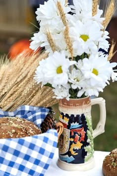 a vase filled with white flowers sitting on top of a table next to muffins