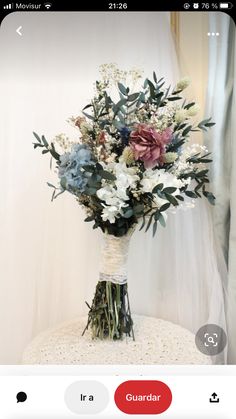 a vase filled with lots of flowers on top of a white table next to a window