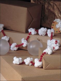 some white and red beads are laying on brown wrapping paper next to small boxes with gifts in the background