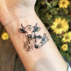 a small cow and calf tattoo on the left wrist, with daisies in the background