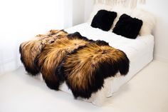 a bed with two black and brown furs on it