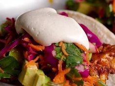 a taco filled with meat, vegetables and sour cream