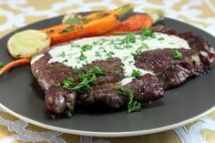 a plate with steak, carrots and bread on it