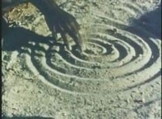 a person standing in front of a circular design on the ground with their hands touching it