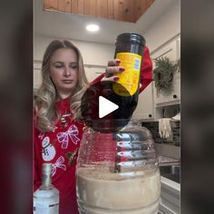 a woman is pouring something into a blender with a bottle on top of it