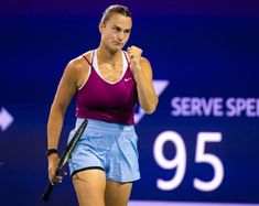 a woman holding a tennis racquet in her right hand and fist raised on the court