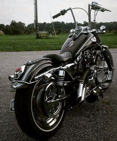 a black motorcycle parked on top of a parking lot next to a lush green field