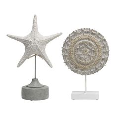 two starfish sculptures on stands one is white and the other is gray with an intricate design