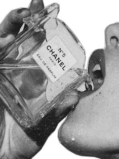 a hand holding a bottle of chanel no 5 perfume in it's mouth