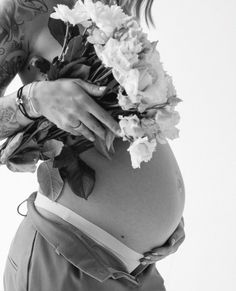 a pregnant woman with flowers on her belly is shown in black and white, while holding the stomach