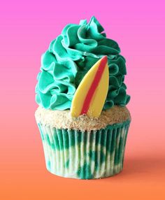 a cupcake with green frosting and a surfboard sticking out of the top