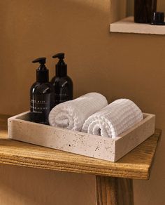 two white towels sitting on top of a wooden shelf next to soap and lotion