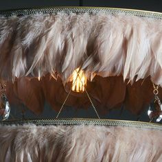 a chandelier with feathers hanging from it's sides and lights in the middle