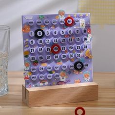 a wooden block with buttons and numbers on it sitting next to a glass of water