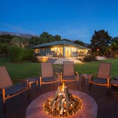 an outdoor fire pit with chairs around it