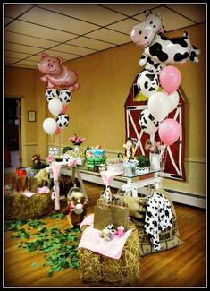 a party with farm animals, balloons and hay bales in the shape of cows