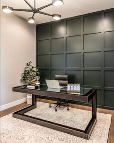 a desk with a laptop on it in front of a green paneled office wall