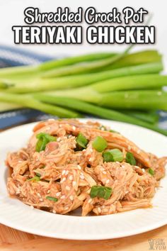 shredded crock pot teriyaki chicken on a white plate with asparagus