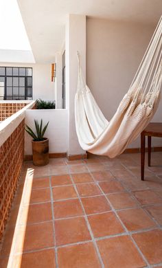 a hammock hanging from the side of a building next to a potted plant